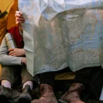 People holding map and sitting in tent